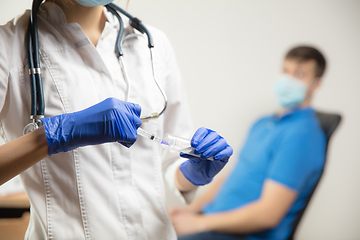 Image showing Doctor or nurse giving vaccine to patient using the syringe injected in hospital