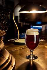 Image showing Glass of stout beer on wooden table in warm light of bar