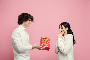 Image showing Young, beautiful couple in love on pink studio background. Valentine\'s Day, love and emotions concept