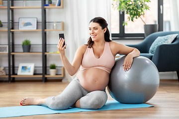 Image showing pregnant woman with phone and fitness ball at home