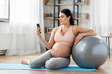 Image showing pregnant woman with phone and fitness ball at home