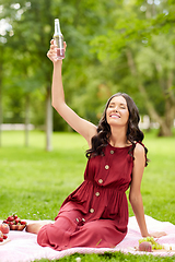 Image showing happy woman toasting drink at picnic in park