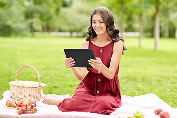 Image showing happy woman with tablet computer on picnic at park