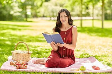 Image showing happy woman reading book at picnic in summer park