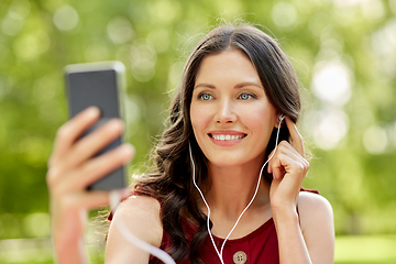 Image showing woman with smartphone and earphones at park