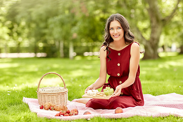 Image showing happy woman with food and picnic basket at park