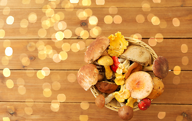 Image showing basket of different edible mushrooms on wood