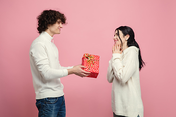 Image showing Young, beautiful couple in love on pink studio background. Valentine\'s Day, love and emotions concept