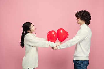 Image showing Young, beautiful couple in love on pink studio background. Valentine\'s Day, love and emotions concept