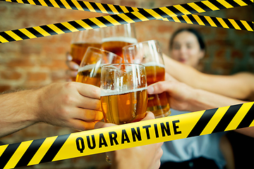 Image showing Close up hands clinking glasses of beer at bar with bounding tapes Lockdown, Coronavirus, Quarantine, Warning - closing bars and nightclubs during pandemic