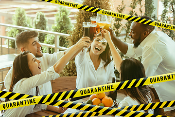 Image showing Group of friends clinking glasses of beer at bar with bounding tapes Lockdown, Coronavirus, Quarantine, Warning - closing bars and nightclubs during pandemic