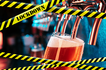 Image showing Hand of bartender pouring a beer in tap with bounding tapes Lockdown, Coronavirus, Quarantine, Warning - closing bars and nightclubs during pandemic