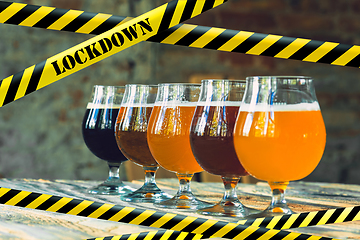 Image showing Glasses of different types of beer at bar with bounding tapes Lockdown, Coronavirus, Quarantine, Warning - closing bars and nightclubs during pandemic