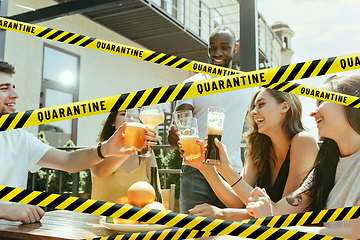 Image showing Group of friends clinking glasses of beer at bar with bounding tapes Lockdown, Coronavirus, Quarantine, Warning - closing bars and nightclubs during pandemic