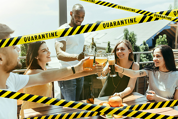 Image showing Group of friends clinking glasses of beer at bar with bounding tapes Lockdown, Coronavirus, Quarantine, Warning - closing bars and nightclubs during pandemic