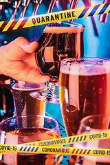 Image showing Hand of bartender pouring a beer in tap with bounding tapes Lockdown, Coronavirus, Quarantine, Warning - closing bars and nightclubs during pandemic