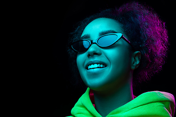 Image showing African-american woman\'s portrait isolated on dark studio background in multicolored neon light