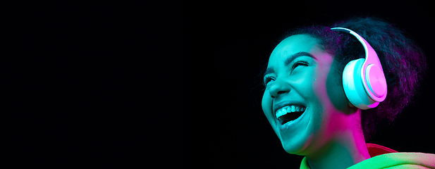 Image showing African-american woman\'s portrait isolated on dark studio background in multicolored neon light