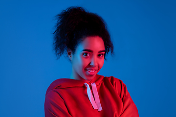 Image showing African-american woman\'s portrait isolated on blue studio background in multicolored neon light