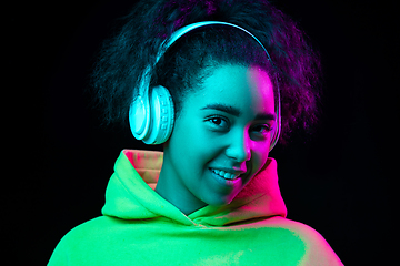 Image showing African-american woman\'s portrait isolated on dark studio background in multicolored neon light