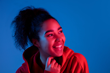 Image showing African-american woman\'s portrait isolated on blue studio background in multicolored neon light