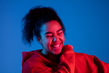 Image showing African-american woman\'s portrait isolated on blue studio background in multicolored neon light