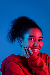 Image showing African-american woman\'s portrait isolated on blue studio background in multicolored neon light