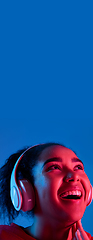 Image showing African-american woman\'s portrait isolated on blue studio background in multicolored neon light