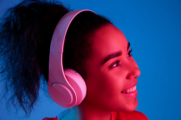 Image showing African-american woman\'s portrait isolated on blue studio background in multicolored neon light