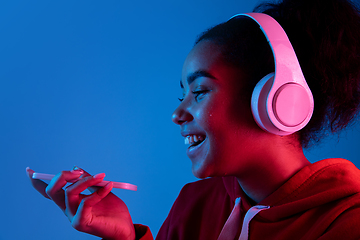 Image showing African-american woman\'s portrait isolated on blue studio background in multicolored neon light