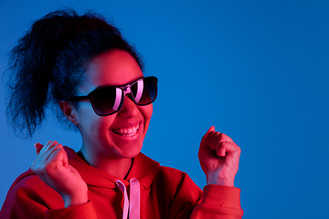 Image showing African-american woman\'s portrait isolated on blue studio background in multicolored neon light