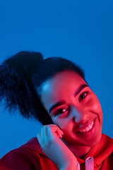 Image showing African-american woman\'s portrait isolated on blue studio background in multicolored neon light