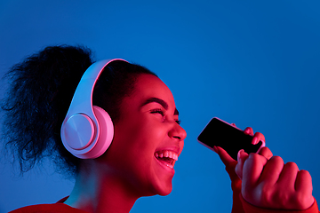 Image showing African-american woman\'s portrait isolated on blue studio background in multicolored neon light