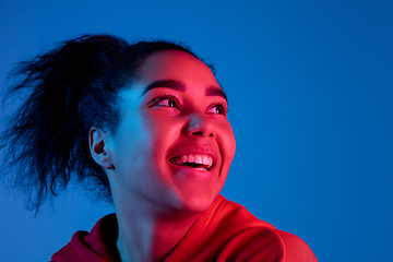 Image showing African-american woman\'s portrait isolated on blue studio background in multicolored neon light