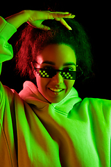 Image showing African-american woman\'s portrait isolated on dark studio background in multicolored neon light