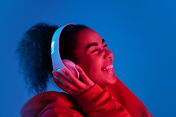 Image showing African-american woman\'s portrait isolated on blue studio background in multicolored neon light