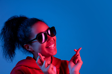 Image showing African-american woman\'s portrait isolated on blue studio background in multicolored neon light