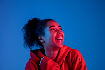 Image showing African-american woman\'s portrait isolated on blue studio background in multicolored neon light