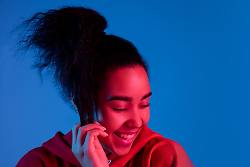 Image showing African-american woman\'s portrait isolated on blue studio background in multicolored neon light