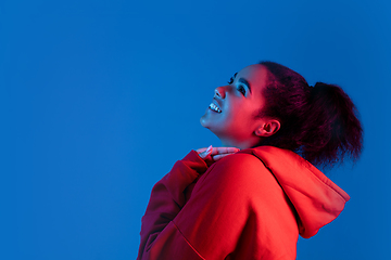 Image showing African-american woman\'s portrait isolated on blue studio background in multicolored neon light