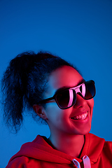 Image showing African-american woman\'s portrait isolated on blue studio background in multicolored neon light