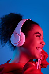 Image showing African-american woman\'s portrait isolated on blue studio background in multicolored neon light