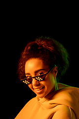 Image showing African-american woman\'s portrait isolated on dark studio background in multicolored neon light