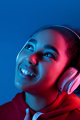 Image showing African-american woman\'s portrait isolated on blue studio background in multicolored neon light