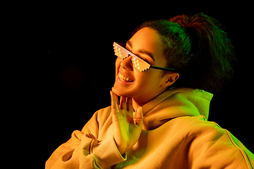 Image showing African-american woman\'s portrait isolated on dark studio background in multicolored neon light