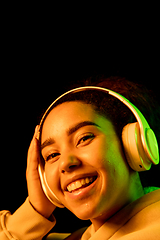 Image showing African-american woman\'s portrait isolated on dark studio background in orange-green neon light