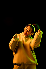 Image showing African-american woman\'s portrait isolated on dark studio background in orange-green neon light