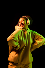 Image showing African-american woman\'s portrait isolated on dark studio background in orange-green neon light