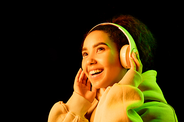 Image showing African-american woman\'s portrait isolated on dark studio background in orange-green neon light