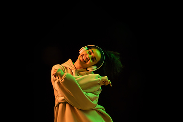 Image showing African-american woman\'s portrait isolated on dark studio background in orange-green neon light